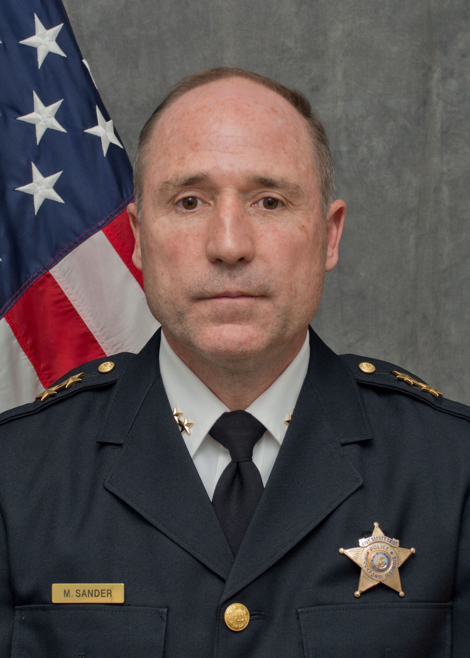 Photo of an Assistant Deputy Chief, man, flag in background