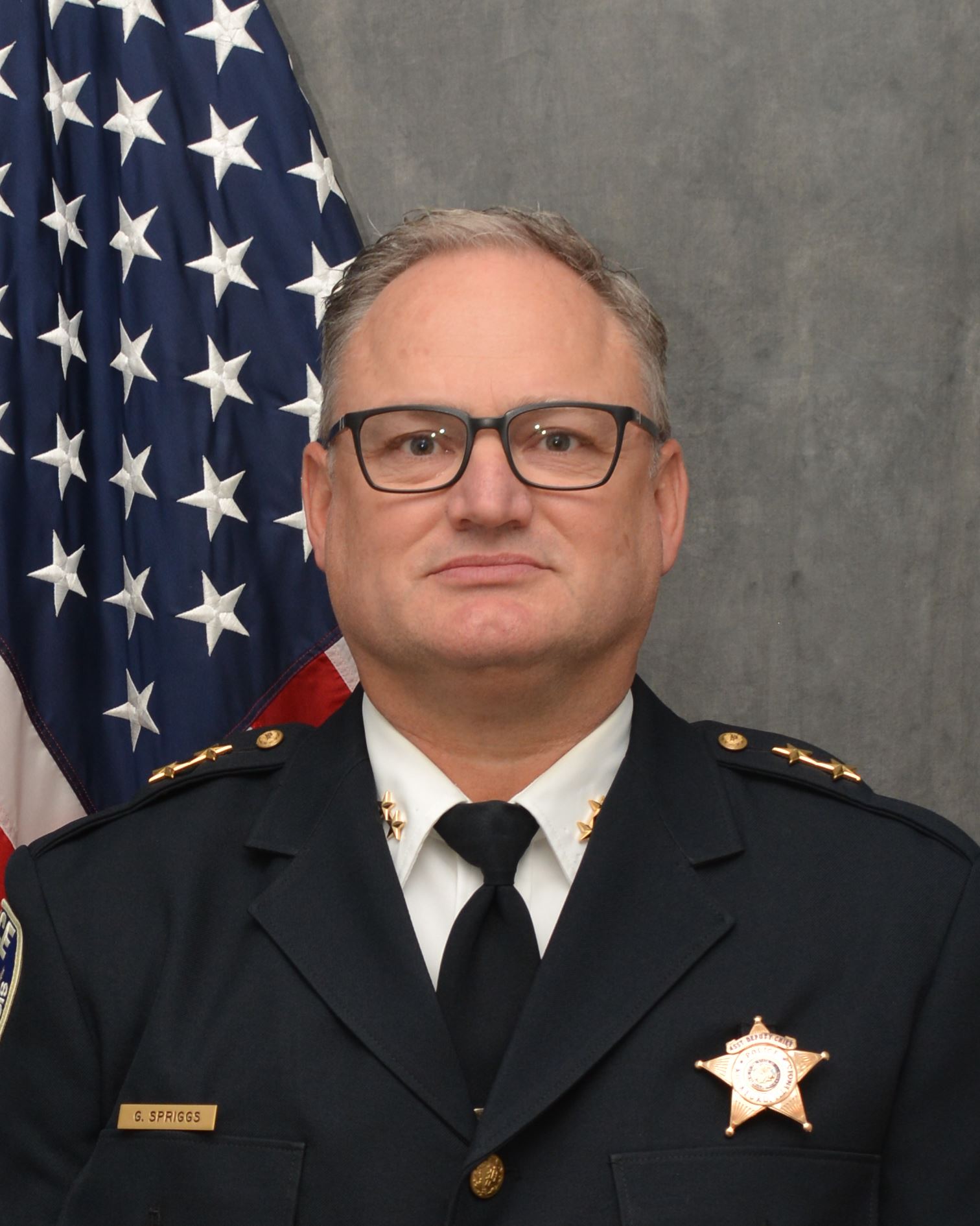 Photo of an Assistant Deputy Chief, man, flag in background